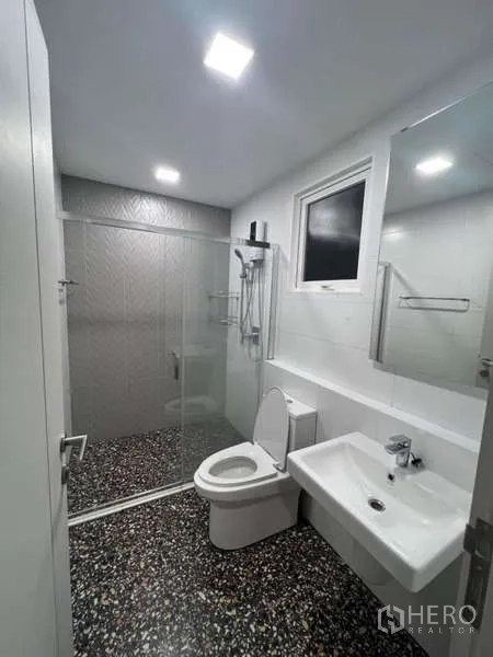 Detached House for rent in Prawet, Bangkok - Bright bathroom with glass shower enclosure, vanity and terrazzo floor.