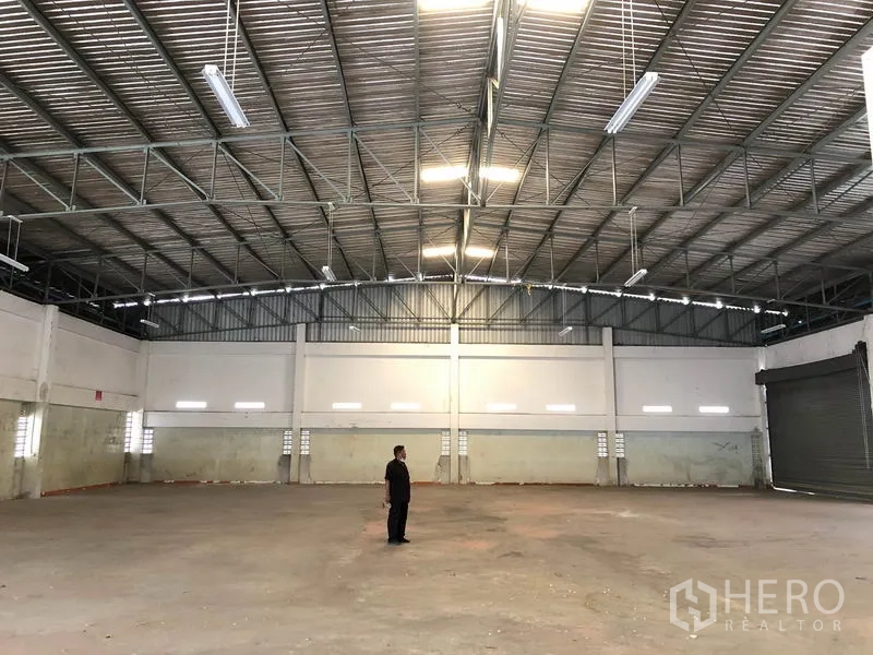 工厂 出租在Nonthaburi - 大跨距仓库内部，灯光明亮，混凝土地面。