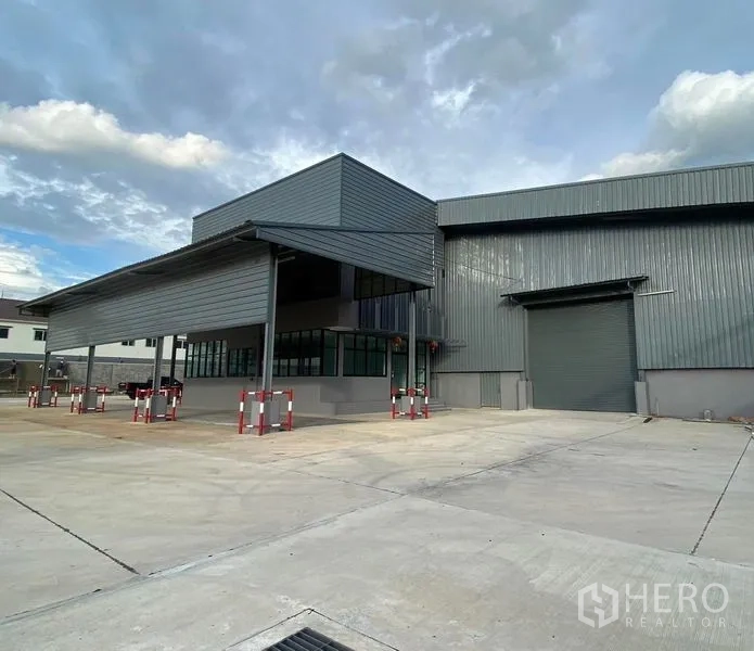 คลังสินค้า ให้เช่าในBang Phli, Samut Prakan - ด้านหน้าอาคารผนังเมทัลชีท พร้อมกันสาดขนาดใหญ่ ประตูม้วน และลานจอดคอนเทนเนอร์กว้าง