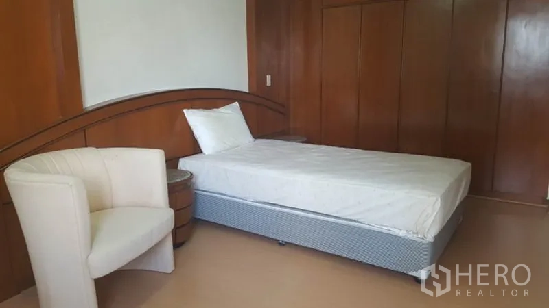 คอนโด ให้เช่าในKhlong Toei, Bangkok - ห้องนอนรองพร้อมเตียงเดี่ยว เก้าอี้นั่งสบาย และตู้เสื้อผ้าบิวท์อิน