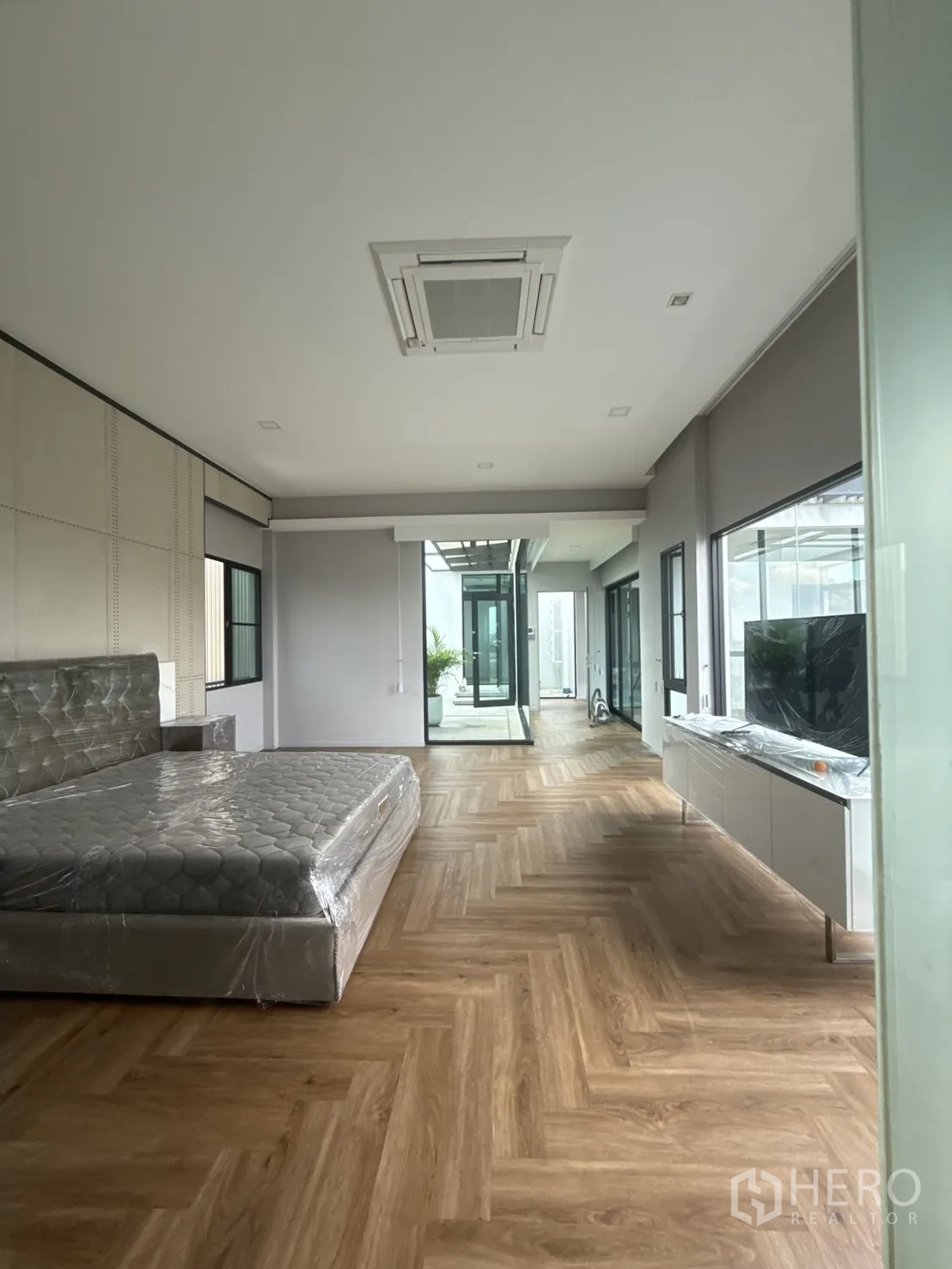 Detached House for rent in Saphan Sung, Bangkok - Primary bedroom with wide layout, herringbone floors and access to an airy corridor.