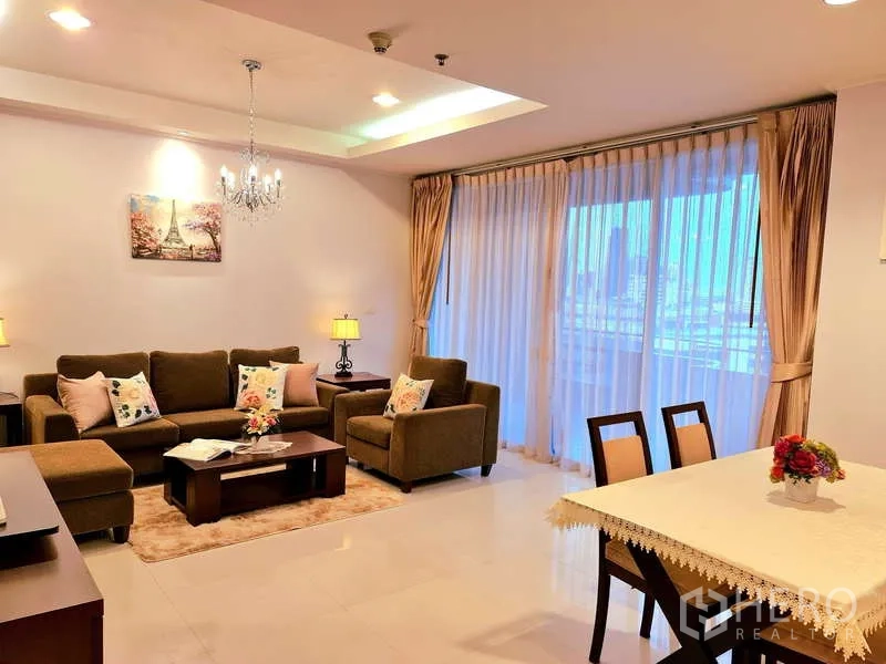 อพาร์ทเมนท์ ให้เช่า - พื้นที่นั่งเล่นและทานข้าวโปร่งสว่าง พร้อมชุดโซฟา โคมแชนเดอเลียร์ และม่านสูงจรดเพดาน
