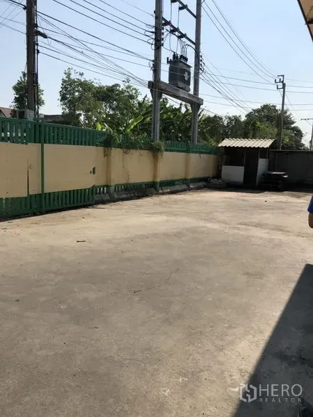 คลังสินค้า ให้เช่าในBueng Kum, Bangkok - ลานคอนกรีตรั้วรอบขอบชิดข้างโกดัง มีแนวสายไฟและป้อมยามขนาดเล็ก.