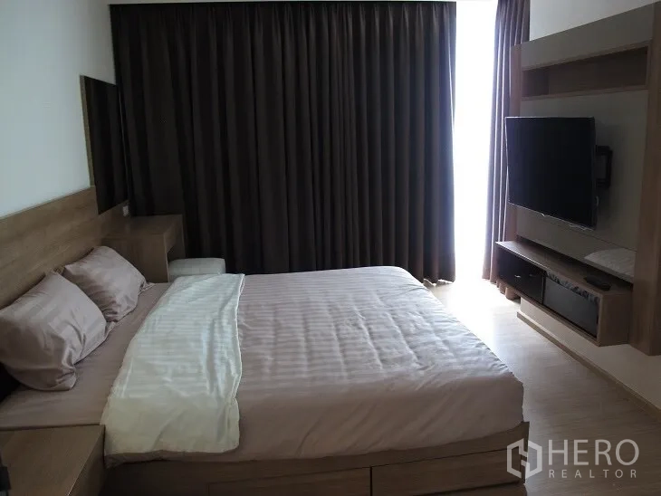 公寓 出租或出售在Khlong Toei, Bangkok - 主卧配大床、深色窗帘与电视柜，氛围温馨。