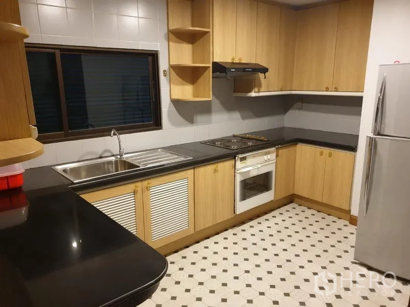 คอนโด ให้เช่าในWatthana, Bangkok - ครัวรูปตัว L ตู้ไม้สีอ่อน เคาน์เตอร์หินแกรนิตสีดำ เตาอบ เตา เครื่องดูดควัน และตู้เย็น