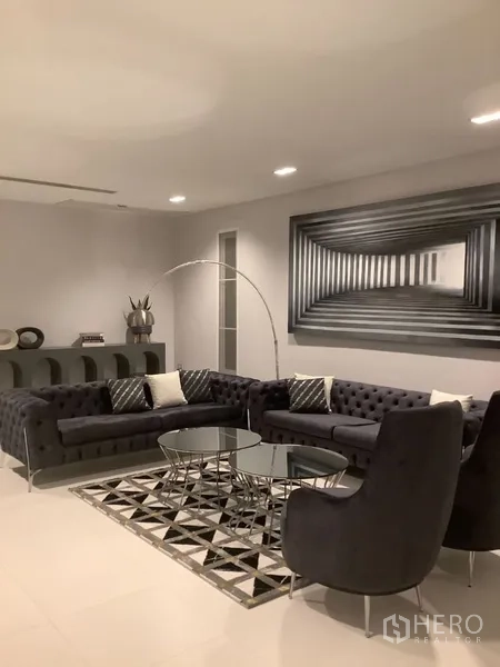 บ้าน ให้เช่าในSuan Luang, Bangkok - ห้องนั่งเล่นสไตล์โมเดิร์น โซฟากำมะหยี่สีเข้ม พรมลายเรขาคณิต และโต๊ะกลาง