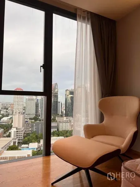Condominium for rent in Khlong Toei, Bangkok - Cozy lounge chair beside a full-height window overlooking the Bangkok skyline.