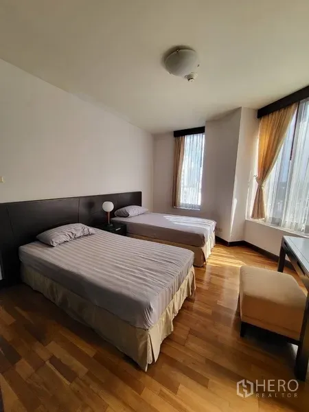 Condominium for rent or sale in Pathum Wan, Bangkok - Guest bedroom featuring two single beds, bedside table and tall windows across polished wood floors.