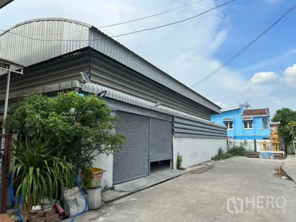货栈 出租在Bueng Kum, Bangkok - 带宽幅卷闸门与波纹金属屋顶的仓库外立面。