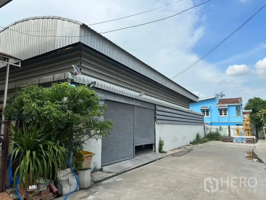 货栈 出租在Bueng Kum, Bangkok - 带宽幅卷闸门与波纹金属屋顶的仓库外立面。