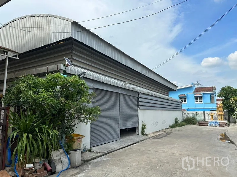 货栈 出租在Bueng Kum, Bangkok - 带宽幅卷闸门与波纹金属屋顶的仓库外立面。