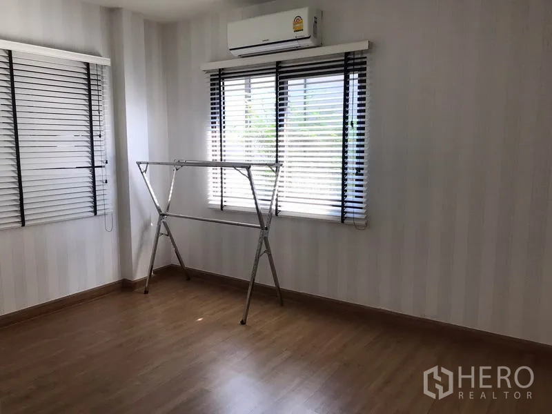 Detached House for rent in Bang Phli, Samut Prakan - Sunlit room with wood flooring, two windows with blinds and wall-mounted air conditioner.