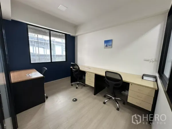 Office Space for rent in Watthana, Bangkok - Bright private office with long desks beneath a window and light wood flooring.