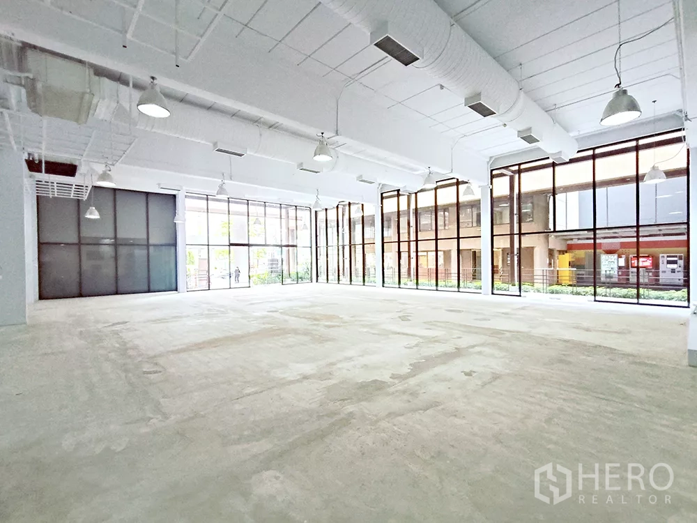 Office Space for rent in Watthana, Bangkok - Large rectangular office area facing floor-to-ceiling glazing and dark-framed double doors.