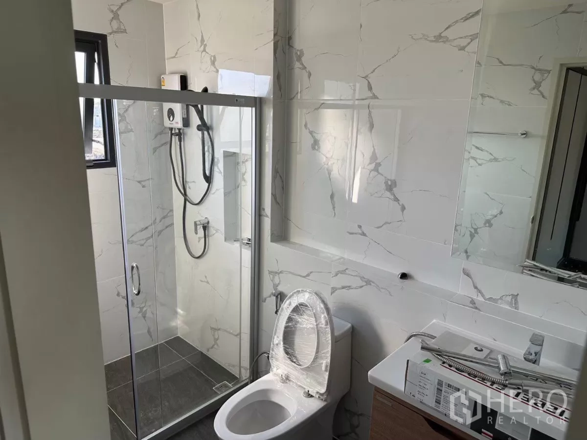 Detached House for rent in Bang Phli, Samut Prakan - Modern bathroom with glass shower enclosure and marble-look tiles.