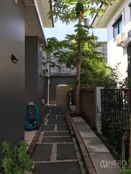 独立式住宅 出租在Bang Kapi, Bangkok - 侧边石板步道，绿树成荫并设有侧门入口。