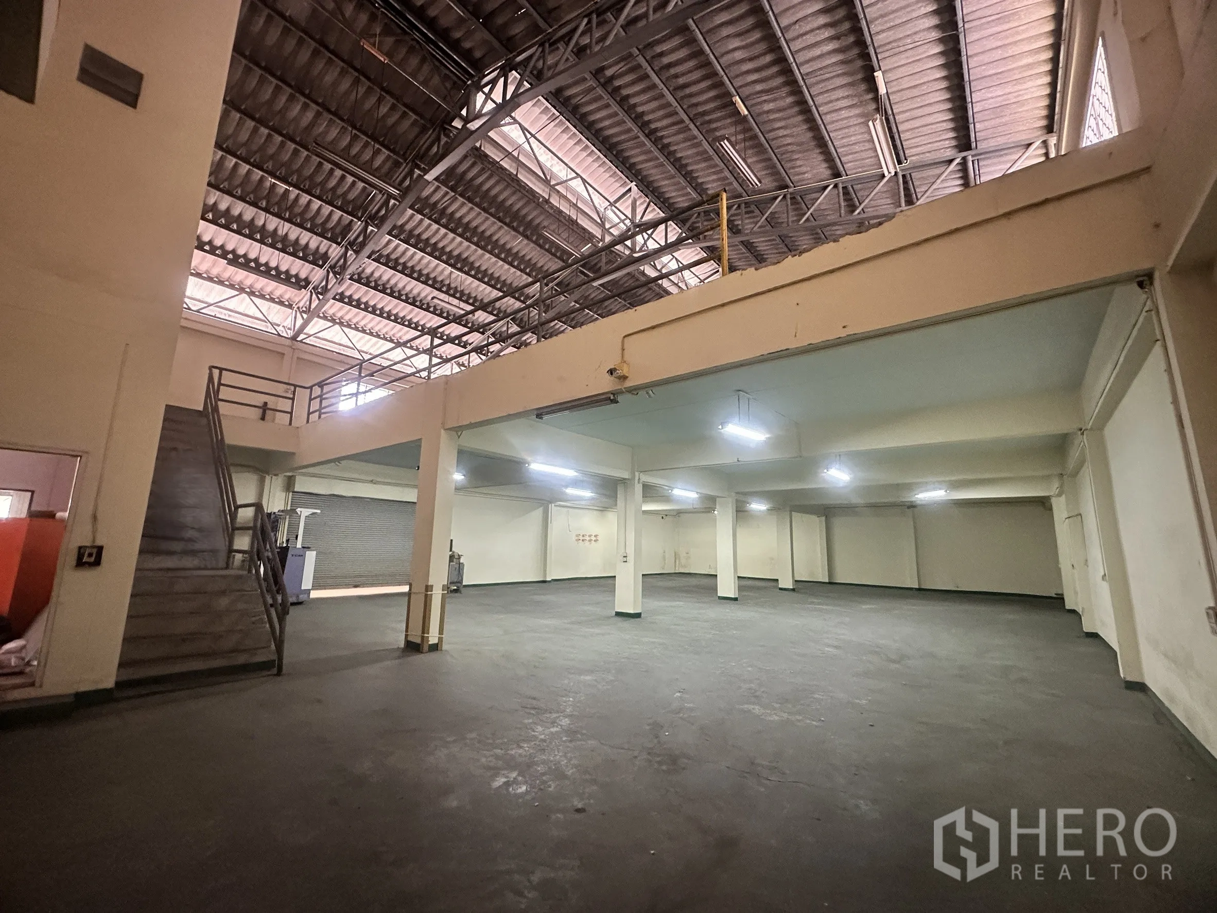 Factory for sale in Bang Bua Thong, Nonthaburi - Spacious warehouse hall with mezzanine, concrete floor, and stairs.