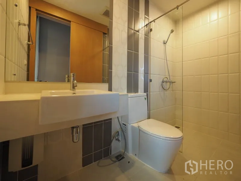 คอนโด ให้เช่าในRatchathewi, Bangkok - ห้องน้ำที่สองพร้อมฝักบัววอล์กอิน สุขภัณฑ์โมเดิร์น และผนังไทล์ลายตัดกัน