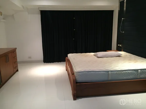 公寓 出租在Khlong Toei, Bangkok - 主卧配木床，白色地砖与遮光窗帘