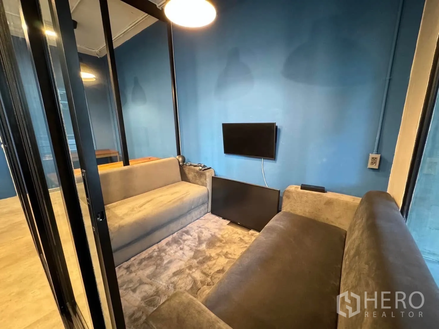 家庭办公室 for rent in Watthana, Bangkok - 私密会谈小间，双人沙发与壁挂电视，位于玻璃门后。