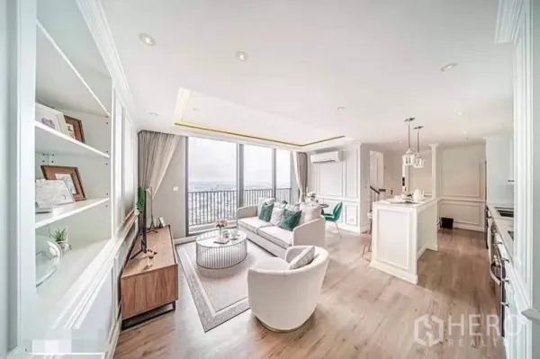 คอนโด ให้เช่าหรือขายในWatthana, Bangkok - ห้องนั่งเล่นสว่างไสว ชั้นวางของบิวท์อิน ชุดโซฟา และวิวสกายไลน์จากผนังกระจกสูง