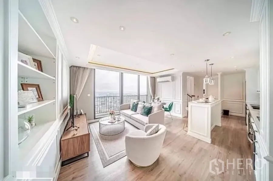 คอนโด ให้เช่าหรือขายในWatthana, Bangkok - ห้องนั่งเล่นสว่างไสว ชั้นวางของบิวท์อิน ชุดโซฟา และวิวสกายไลน์จากผนังกระจกสูง