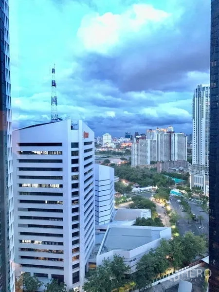 Condominium for rent or sale in Huai Khwang, Bangkok - Evening skyline of Bangkok with illuminated buildings and dramatic clouds.