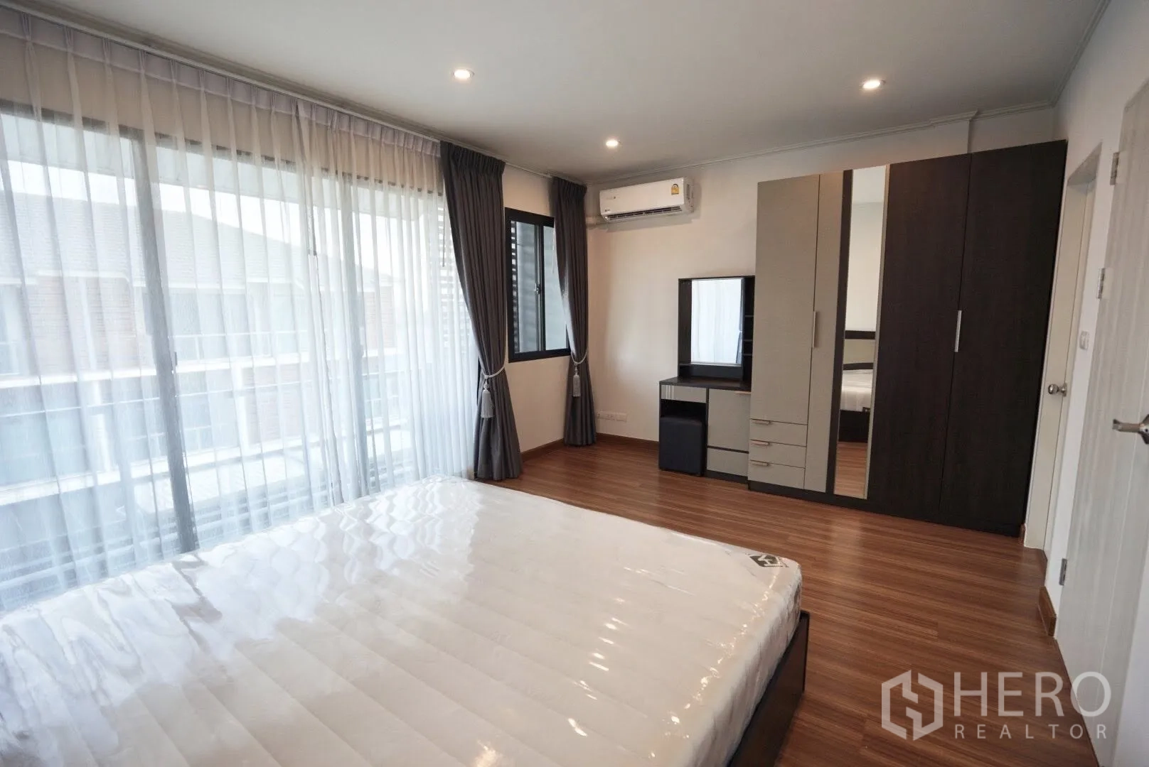 Townhouse for rent in Bang Kapi, Bangkok - Bedroom with king mattress, wardrobes, dressing table and wall-mounted air conditioner.