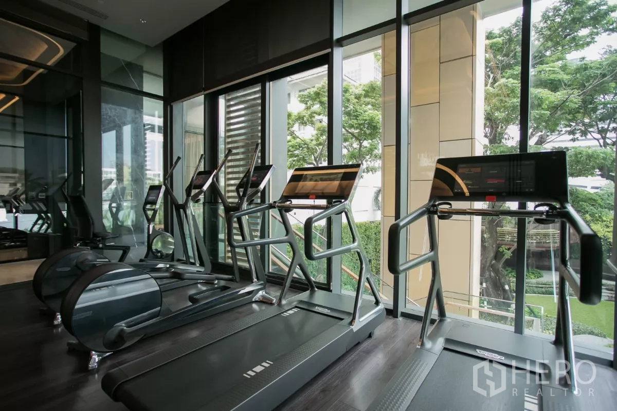 公寓 出租在Watthana, Bangkok - 心肺训练区，落地窗旁跑步机，眺望绿意。