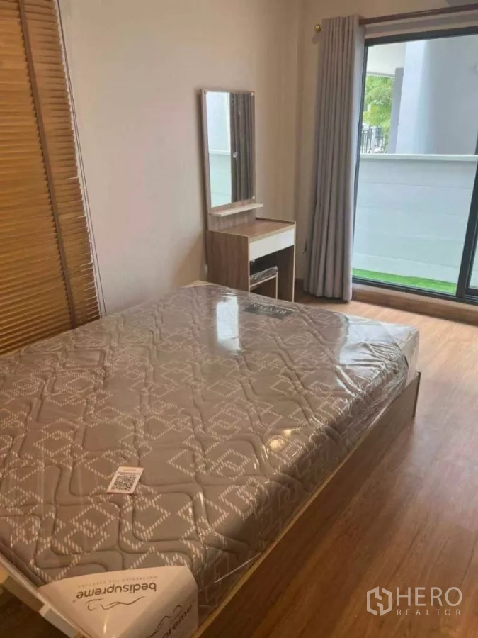 Detached House for rent in Bang Phli, Samut Prakan - Bedroom with balcony access, dressing table and wood flooring.