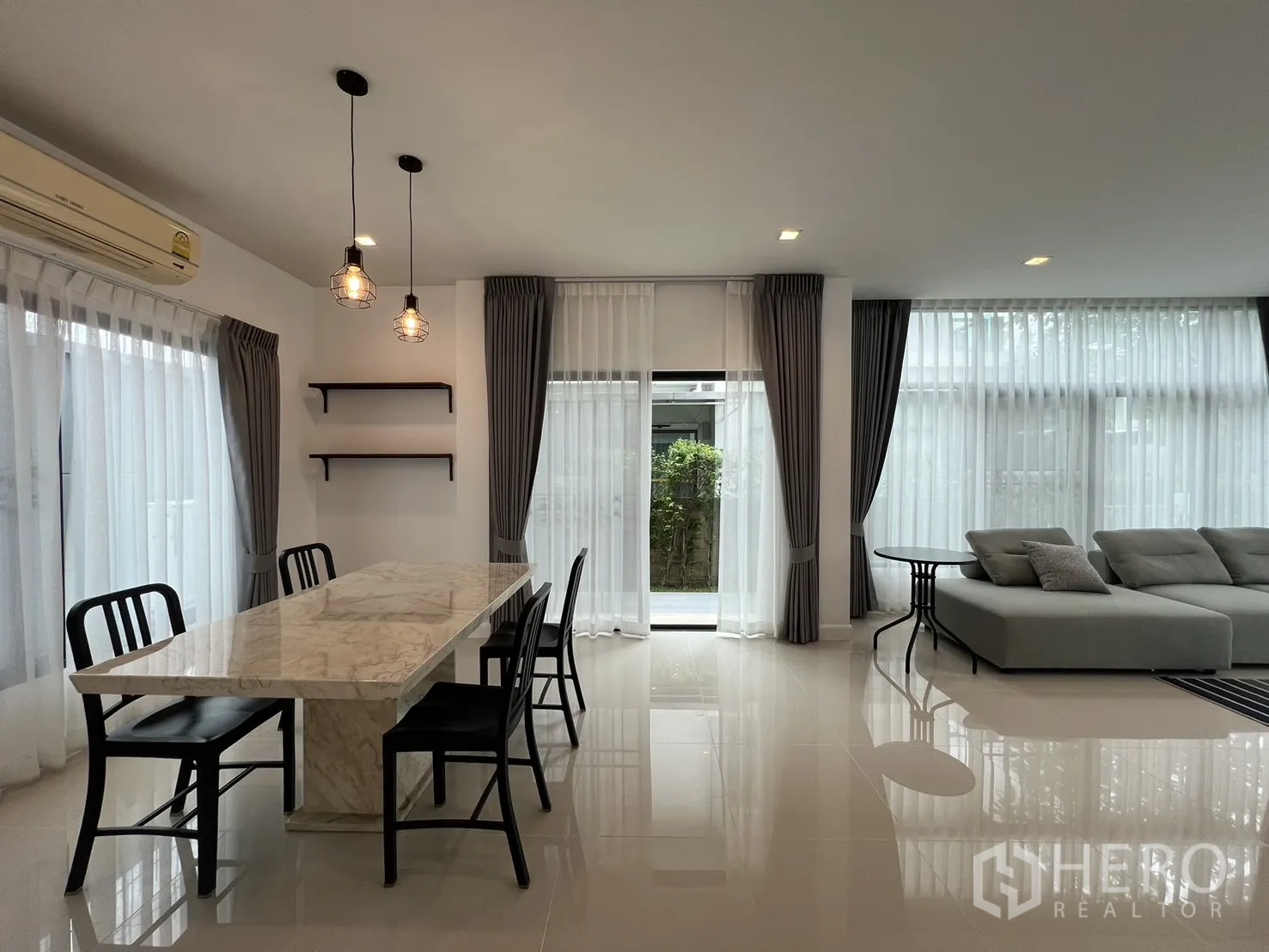 独立式住宅 出租在Bang Kapi, Bangkok - 通透房间，展示餐桌与沙发及成排窗帘。