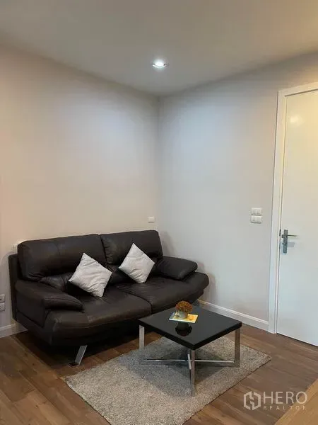 คอนโด ให้เช่าหรือขายในPhra Khanong, Bangkok - มุมโซฟาอบอุ่นพร้อมโต๊ะกาแฟและพรม บนพื้นไม้ ผนังโทนเรียบ