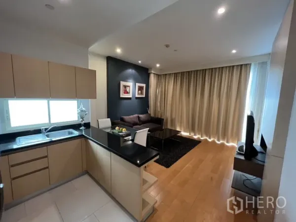 公寓 出租在Chatuchak, Bangkok - L形厨房黑色台面，可眺望客厅与整面落地窗帘。