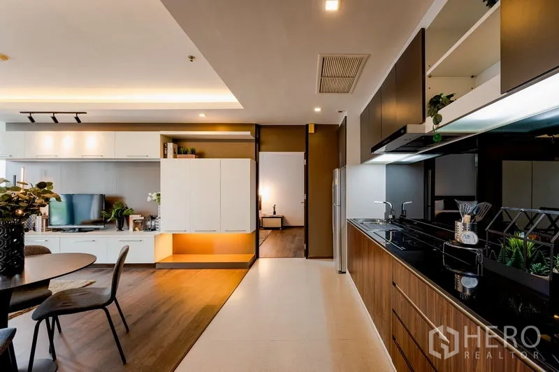 公寓 出售在Khlong Toei, Bangkok - 从厨房望向客厅的视角，收纳柜、餐桌与卧室入口。