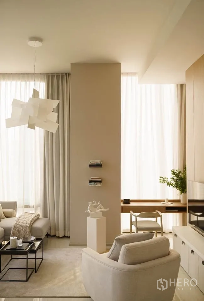 Condominium for rent in Bang Rak, Bangkok - Lounge with armchair, desk nook by the window, and sheer curtains.
