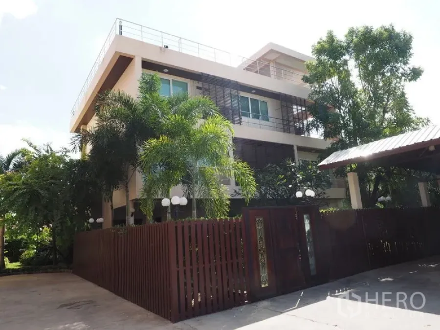 Home Office for sale in Phra Khanong, Bangkok - Gated modern three-storey residence with palm trees and a wide entrance.