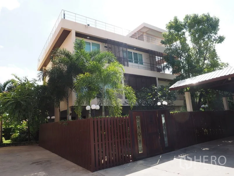Home Office for sale in Phra Khanong, Bangkok - Gated modern three-storey residence with palm trees and a wide entrance.