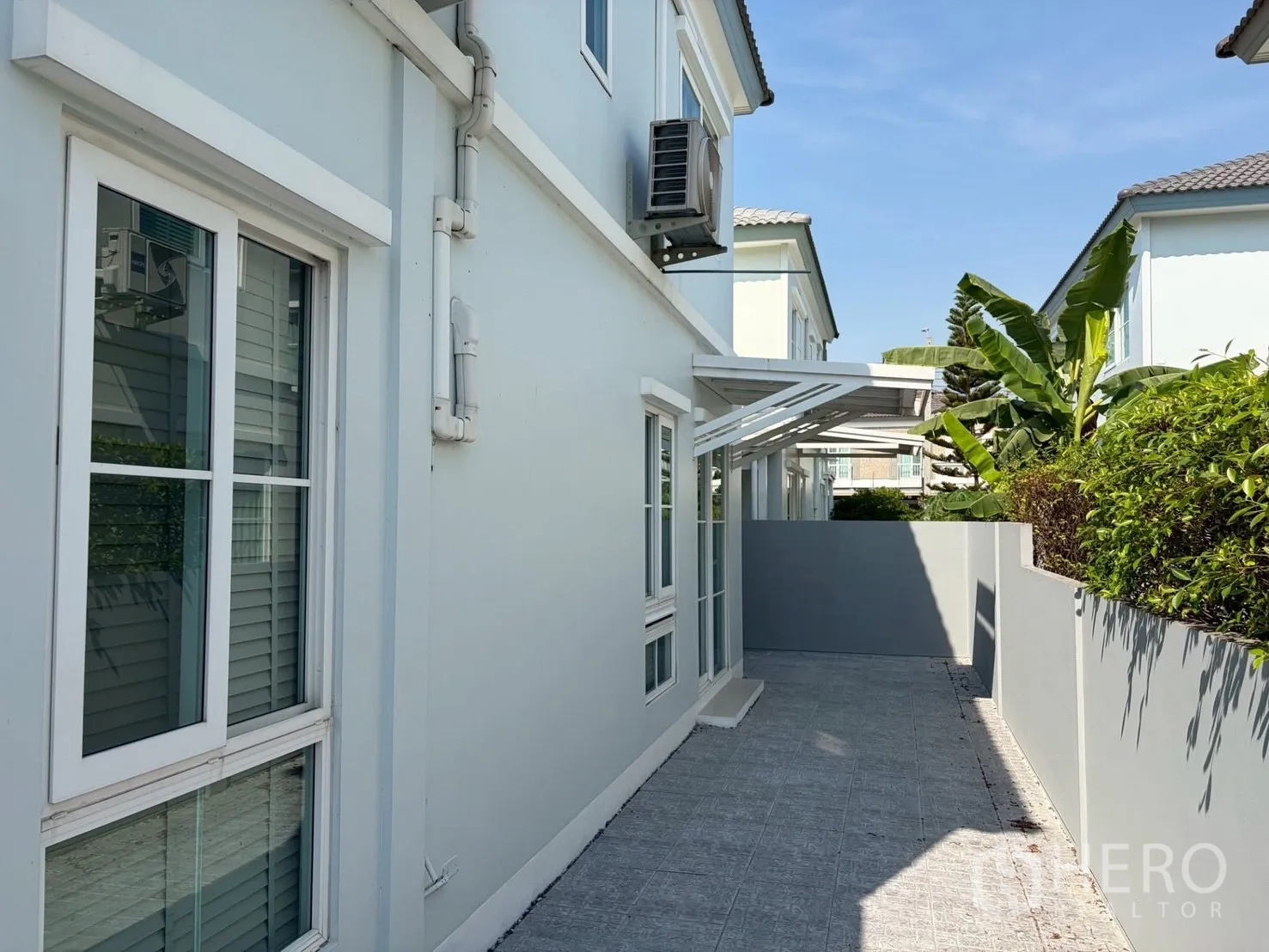 บ้านแฝด for rent in Prawet, Bangkok - ทางเดินข้างบ้านปูกระเบื้อง มีกำแพงและต้นไม้พุ่ม ใกล้หน้าต่างบานเลื่อน