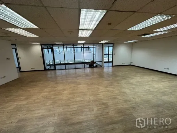 สำนักงาน ให้เช่า - พื้นที่ทำงานโล่งกว้าง พื้นลายไม้ และไฟเพดานฟลูออเรสเซนต์หน้าห้องกระจก