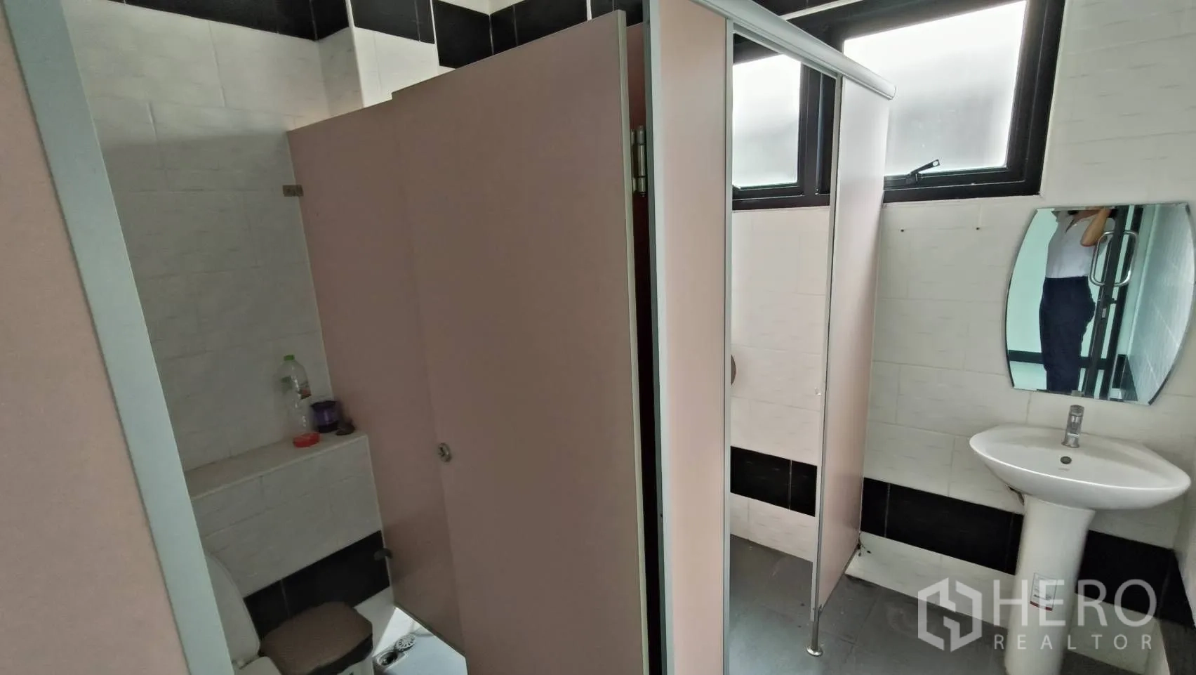 Office Space for rent in Khlong Toei, Bangkok - Restroom with partitioned stalls, a sink and a window.