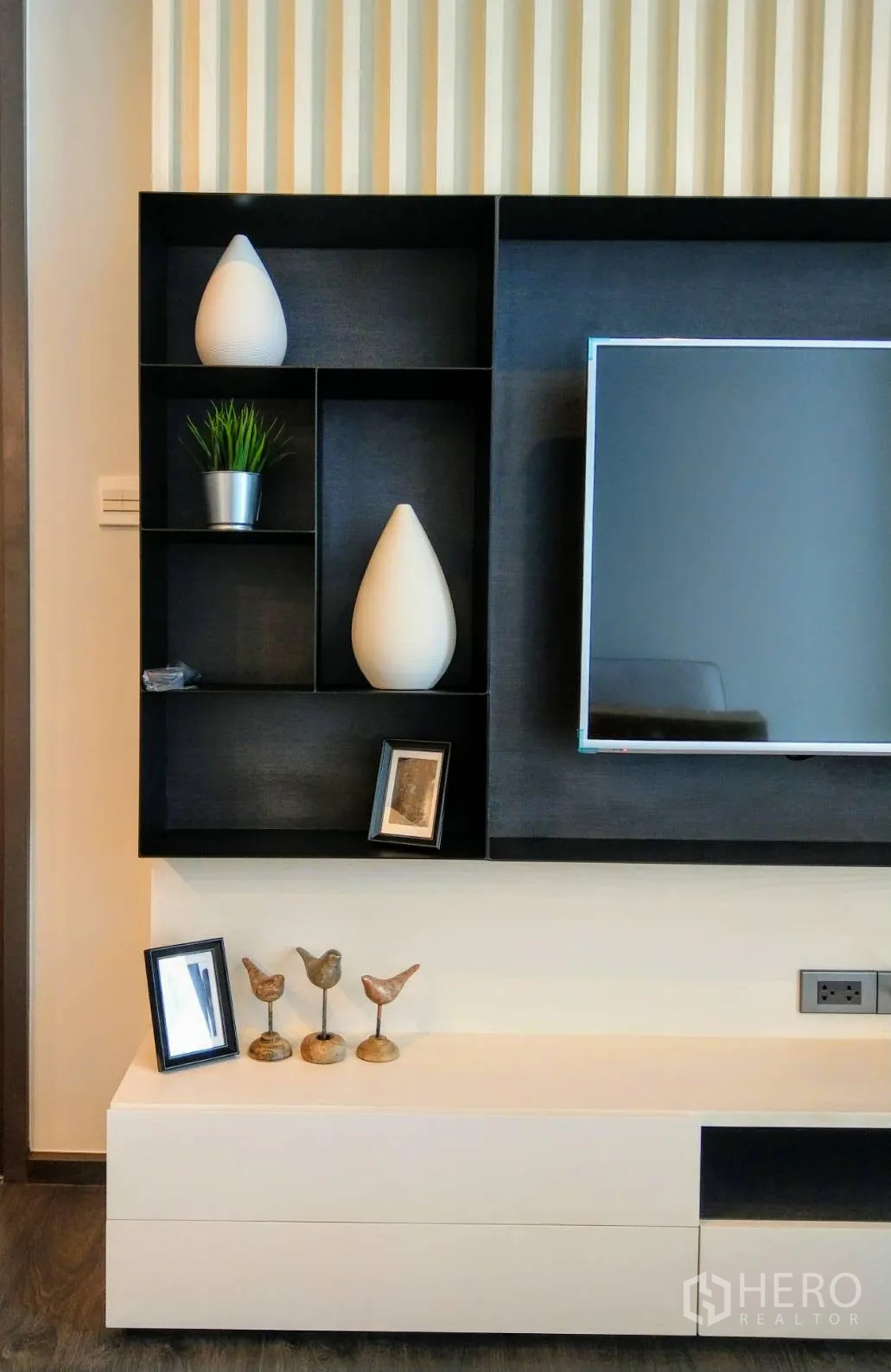 公寓 出租在Watthana, Bangkok - 客厅黑白一体的电视墙与开放式置物格及装饰品。