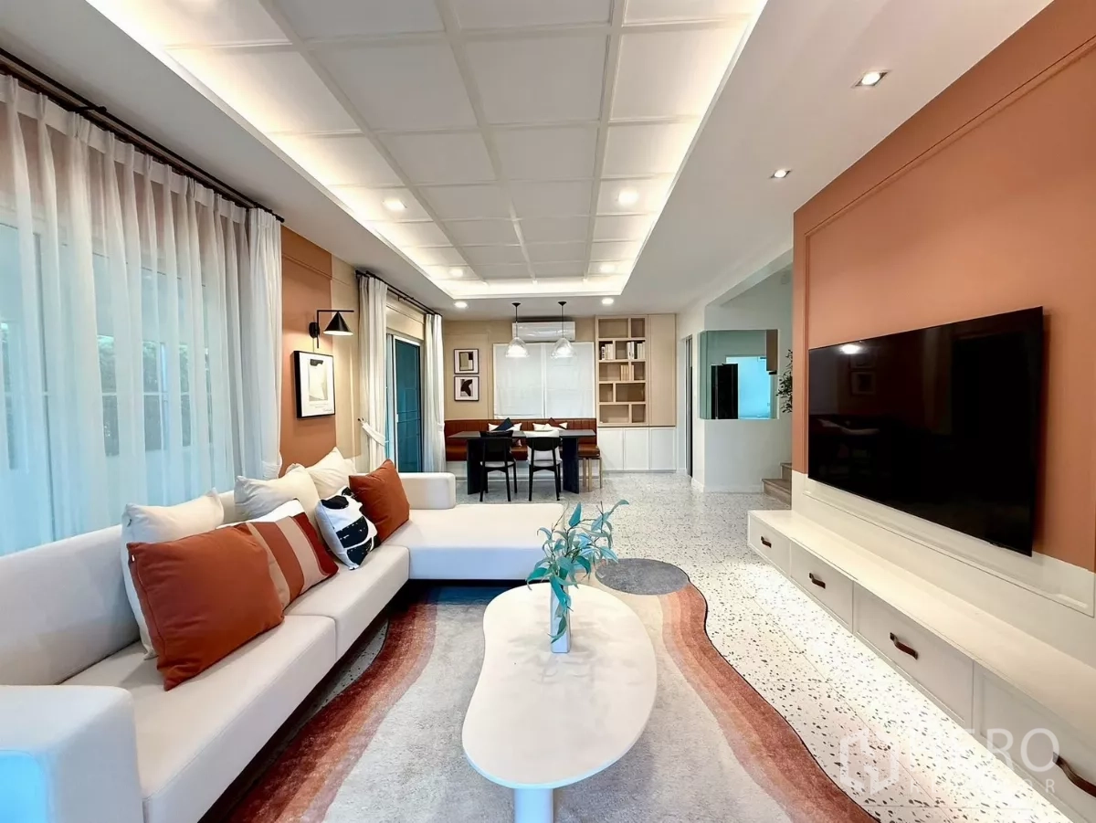 Detached House for rent in Bang Phli, Samut Prakan - Stylish living area with L‑shaped sofa, large TV wall and dining space beyond.