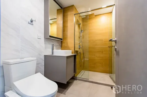 คอนโด ให้เช่าในWatthana, Bangkok - ห้องน้ำสมัยใหม่พร้อมตู้ฝักบัวกระจก อ่างล้างหน้า และโถสุขภัณฑ์ ผนังลายไม้