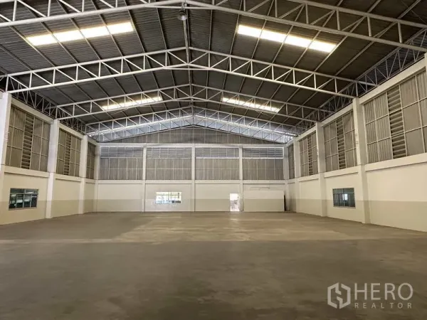 工厂 出租在Samut Prakan - 宽敞仓库内部，高钢结构屋顶、混凝土地面与充足照明。
