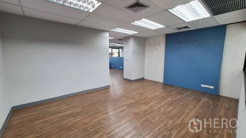 Office Space for rent in Watthana, Bangkok - Spacious office area with wood laminate flooring and a white brick feature wall.