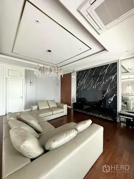 Detached House for sale - Living room featuring a marble TV wall, leather sofas and a crystal chandelier.