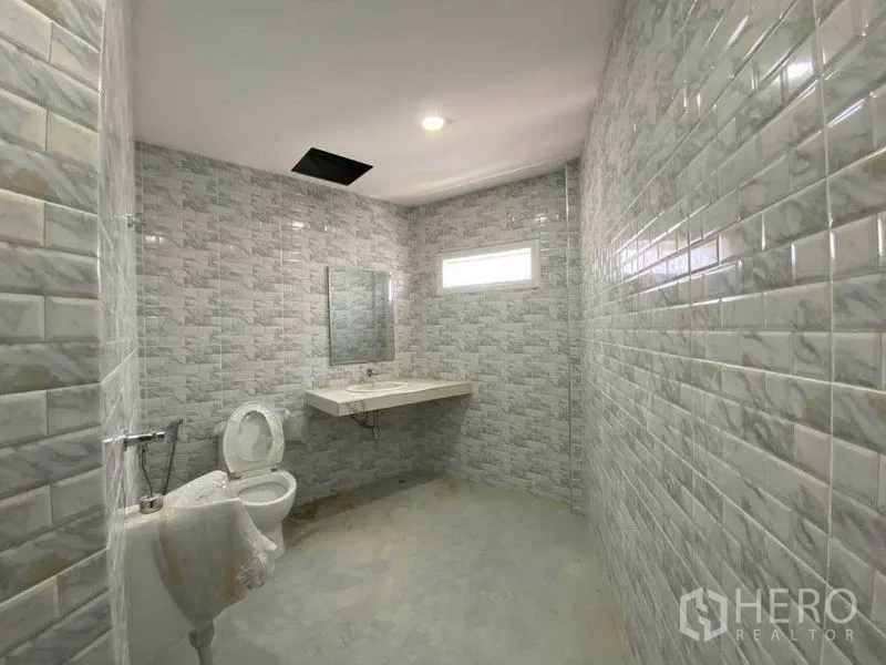 พื้นที่ขายปลีก ให้เช่าในKhlong Toei, Bangkok - ห้องน้ำกว้าง ผนังกระเบื้องสีเทา พร้อมโถสุขภัณฑ์และเคาน์เตอร์ล้างมือ