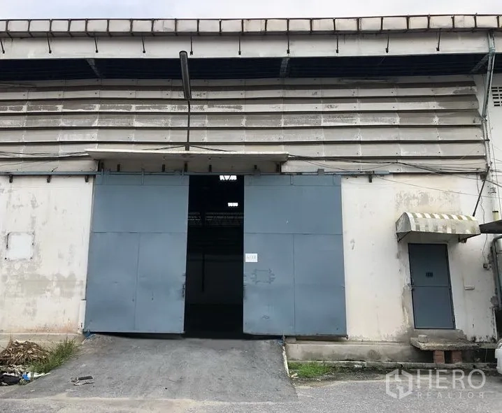คลังสินค้า ให้เช่าในBang Phli, Samut Prakan - ด้านหน้าโกดัง ประตูเหล็กบานเลื่อนขนาดใหญ่ มีทางลาดและประตูคนเดิน