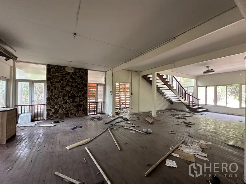 Detached House for rent in Watthana, Bangkok - Spacious living area with wood floors, a stone feature wall and staircase.