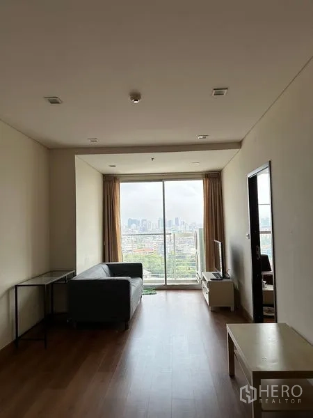 Condominium for sale in Watthana, Bangkok - Open living-dining area leading to balcony, wood floors and sofa.